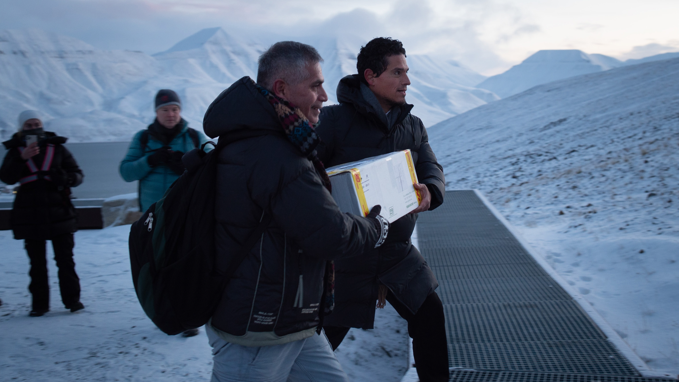 Two men carry a box